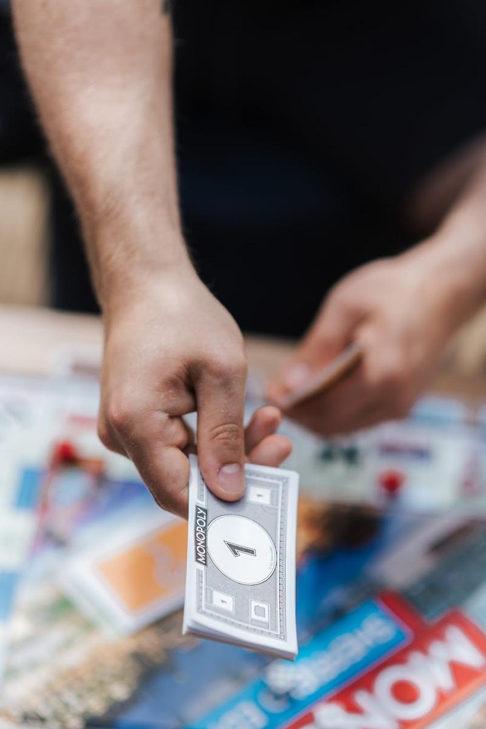 close_up_photo_of_person_handing_out_fake_monopoly