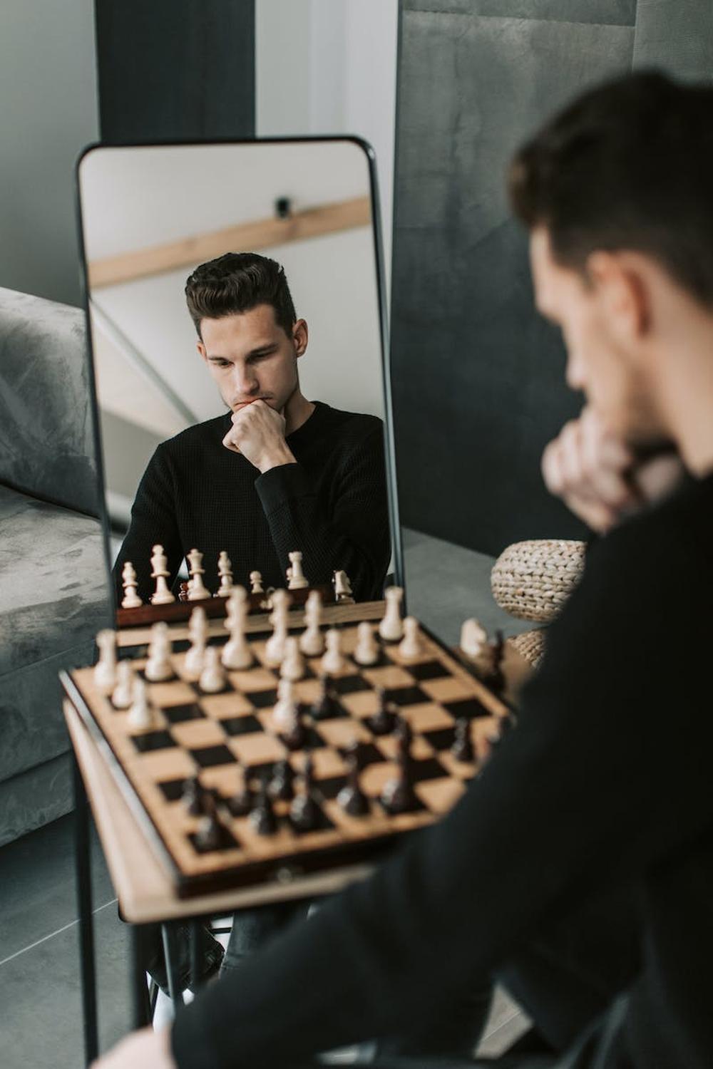 man_in_black_sweater_sitting_beside_chess_board