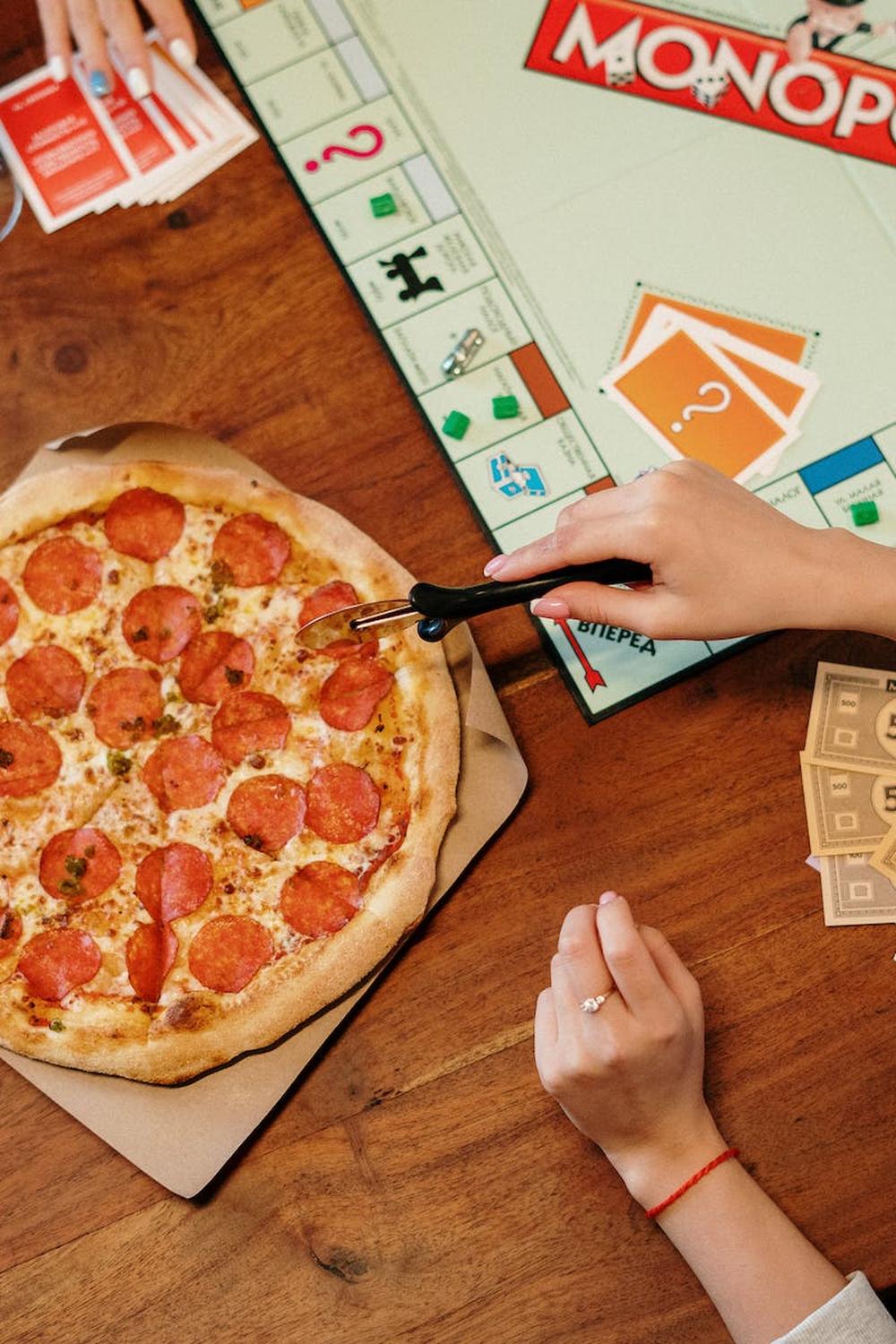 pizza_and_monopoly_board_game_on_wooden_surface